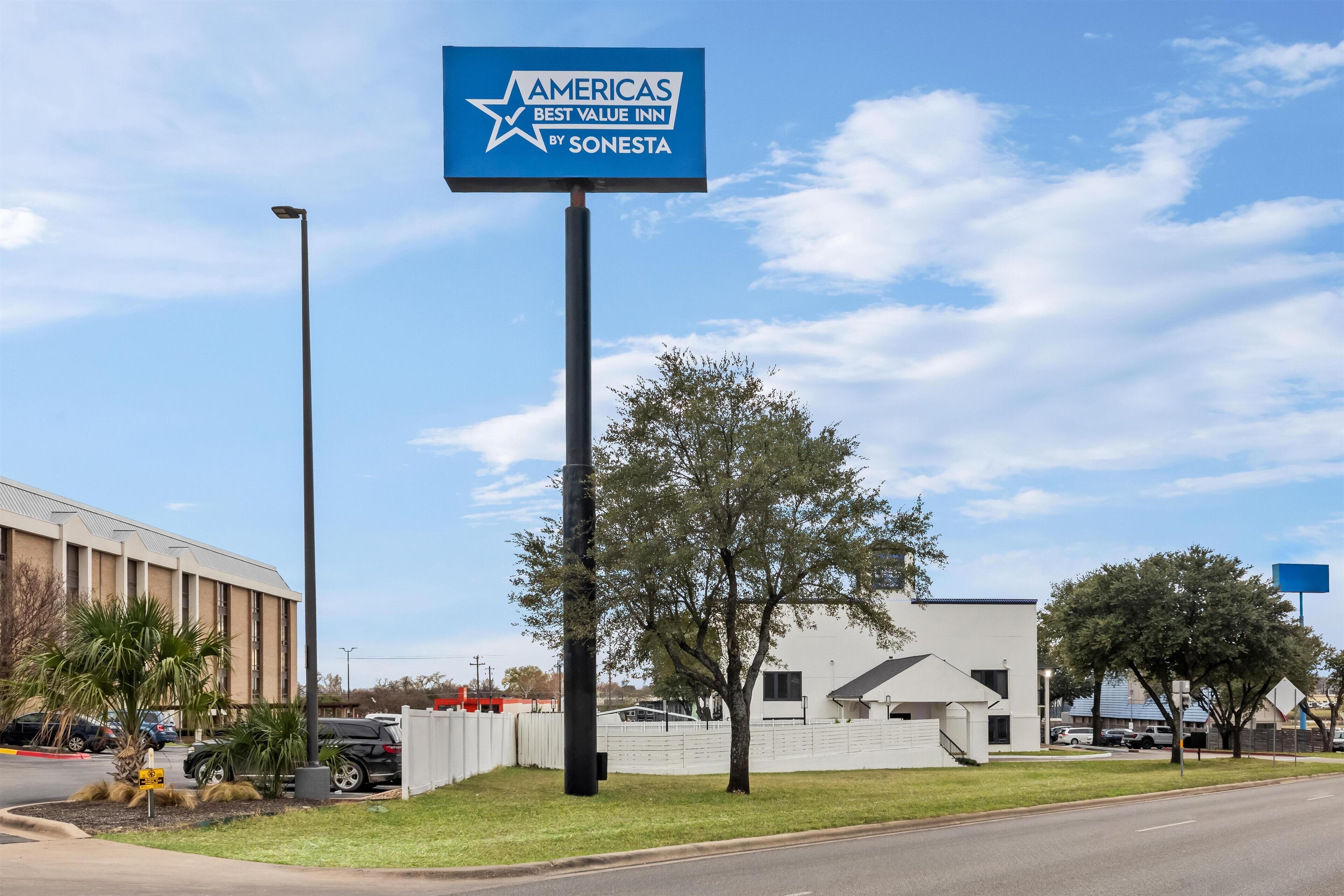 Señal del hotel Amerias Best Value Inn by Sonesta, un edificio de diseño moderno y un estacionamiento con automóviles.