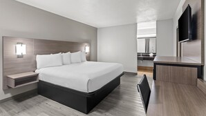 Ein modernes Hotelzimmer mit einem großen Bett, Nachttischen, einem Schreibtisch und einem an der Wand befestigten Flachbildfernseher.