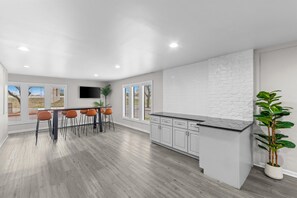 A modern kitchen with a large island, white cabinetry, and a flat-screen TV mounted above the island.