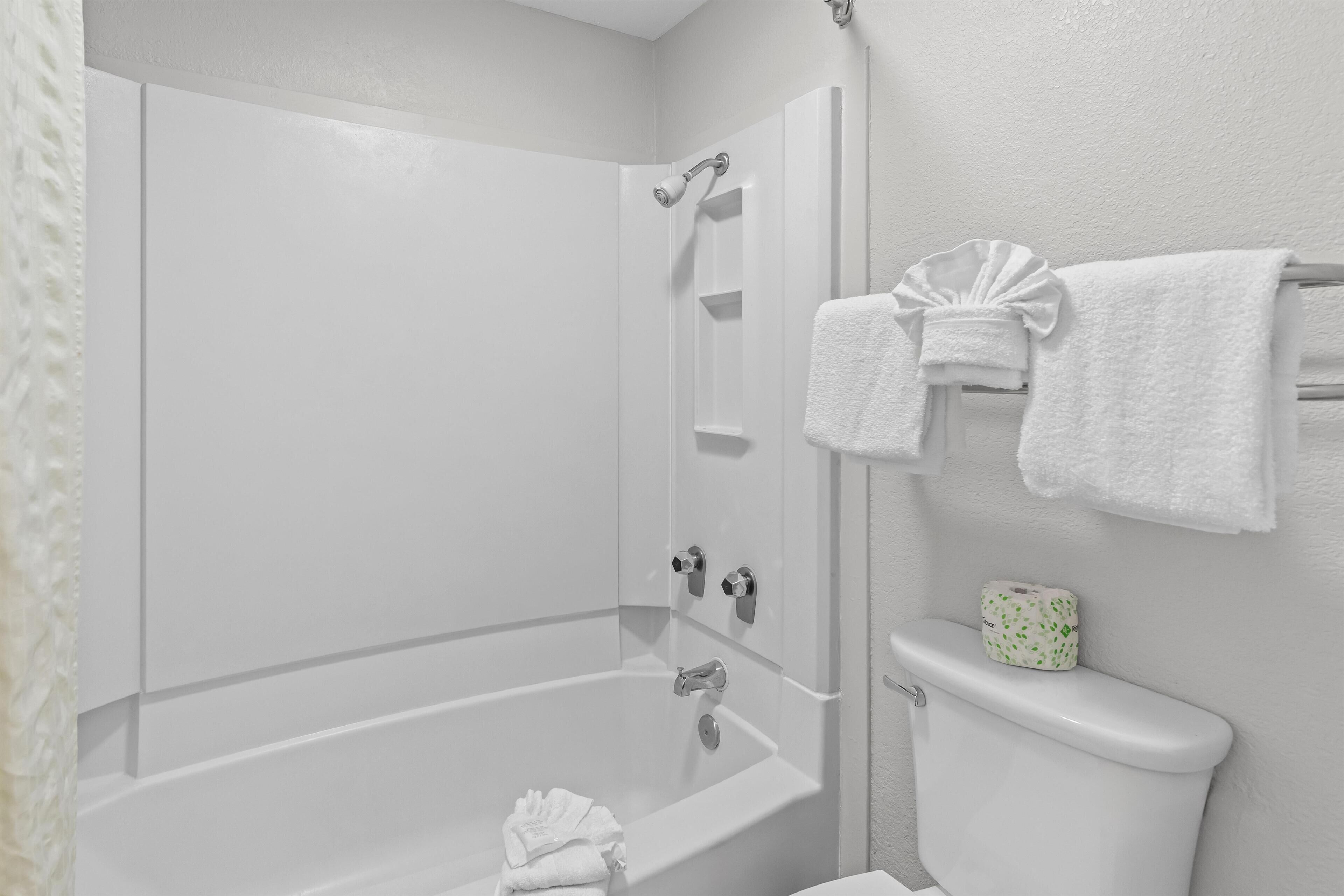 A bathroom with a bathtub, toilet, and a towel rack.