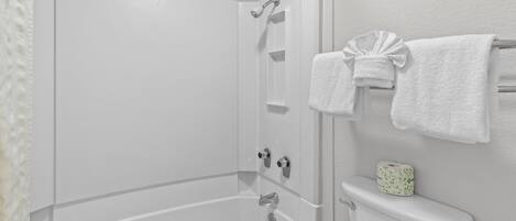 A bathroom with a bathtub, toilet, and a towel rack.