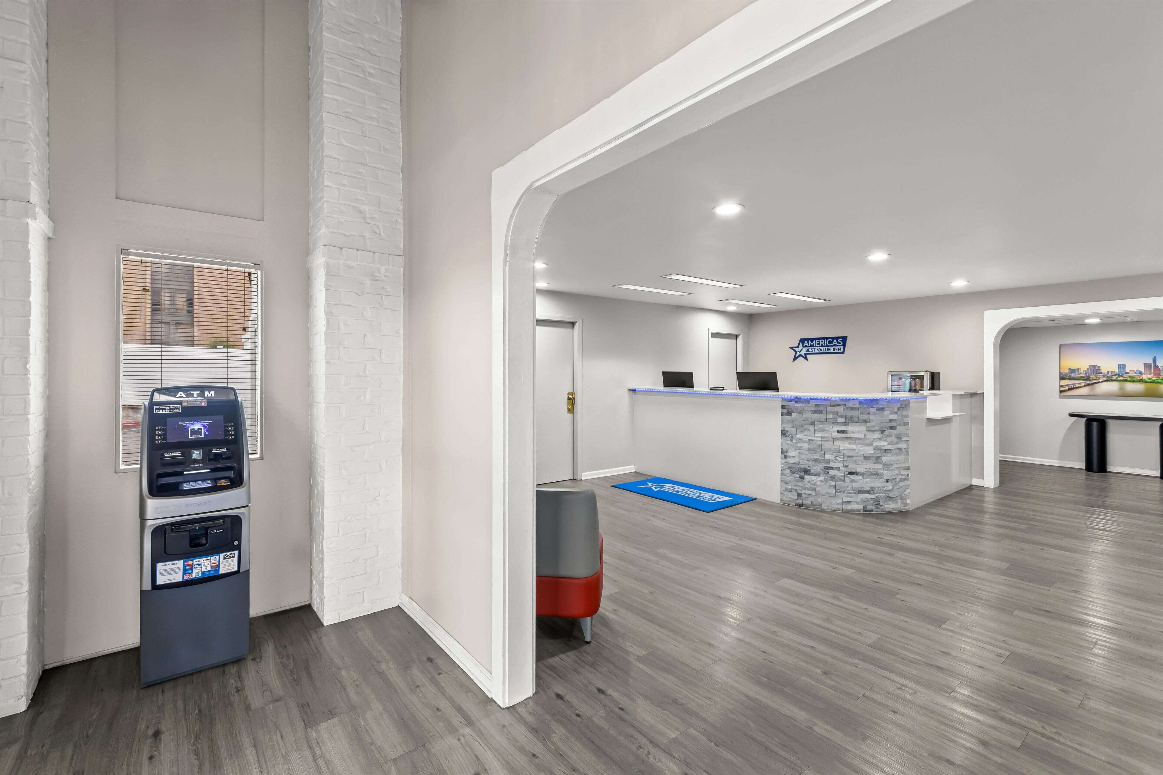 A modern reception area with a reception desk, a blue mat, and an ATM machine.