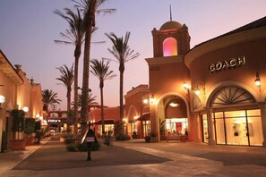 A hotel with a prominent 'COACH' sign, palm trees, and a sunset sky. - Rodeway Inn San Diego South San Ysidro Border (San Ysidro)