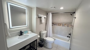 A modern bathroom with a large mirror, a sink, a toilet, and a shower.