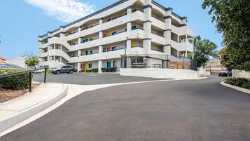 Un immeuble résidentiel à plusieurs étages, doté de balcons, d’une entrée sécurisée et d’un espace de stationnement.