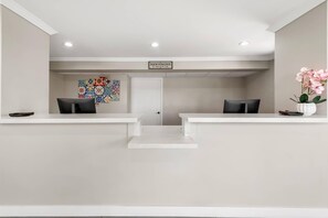 A reception area with two reception desks, a welcome sign, a colorful tile wall, and a potted orchid. - Rodeway Inn San Diego South San Ysidro Border (San Ysidro)