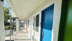 A corridor with doors, a concrete floor, and a covered walkway.