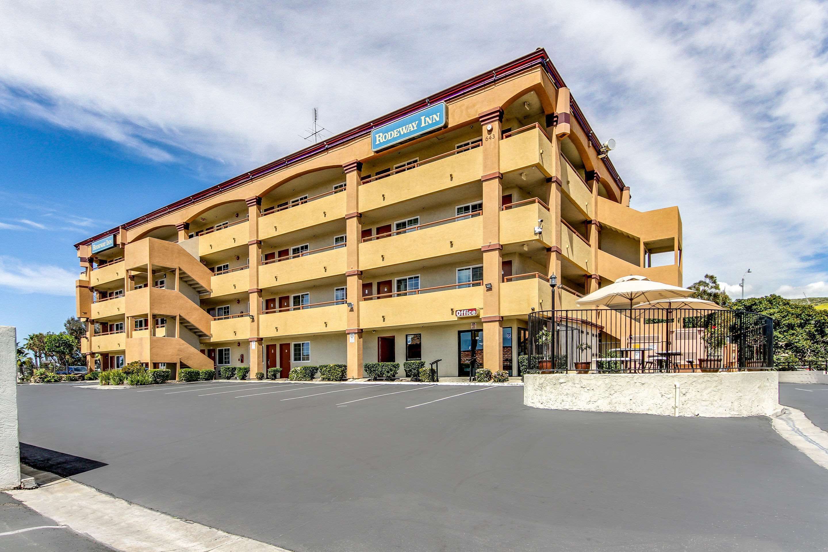 Un hotel de varios pisos con un letrero que dice 'Rodeway Inn' y un letrero de 'Oficina' en la planta baja.