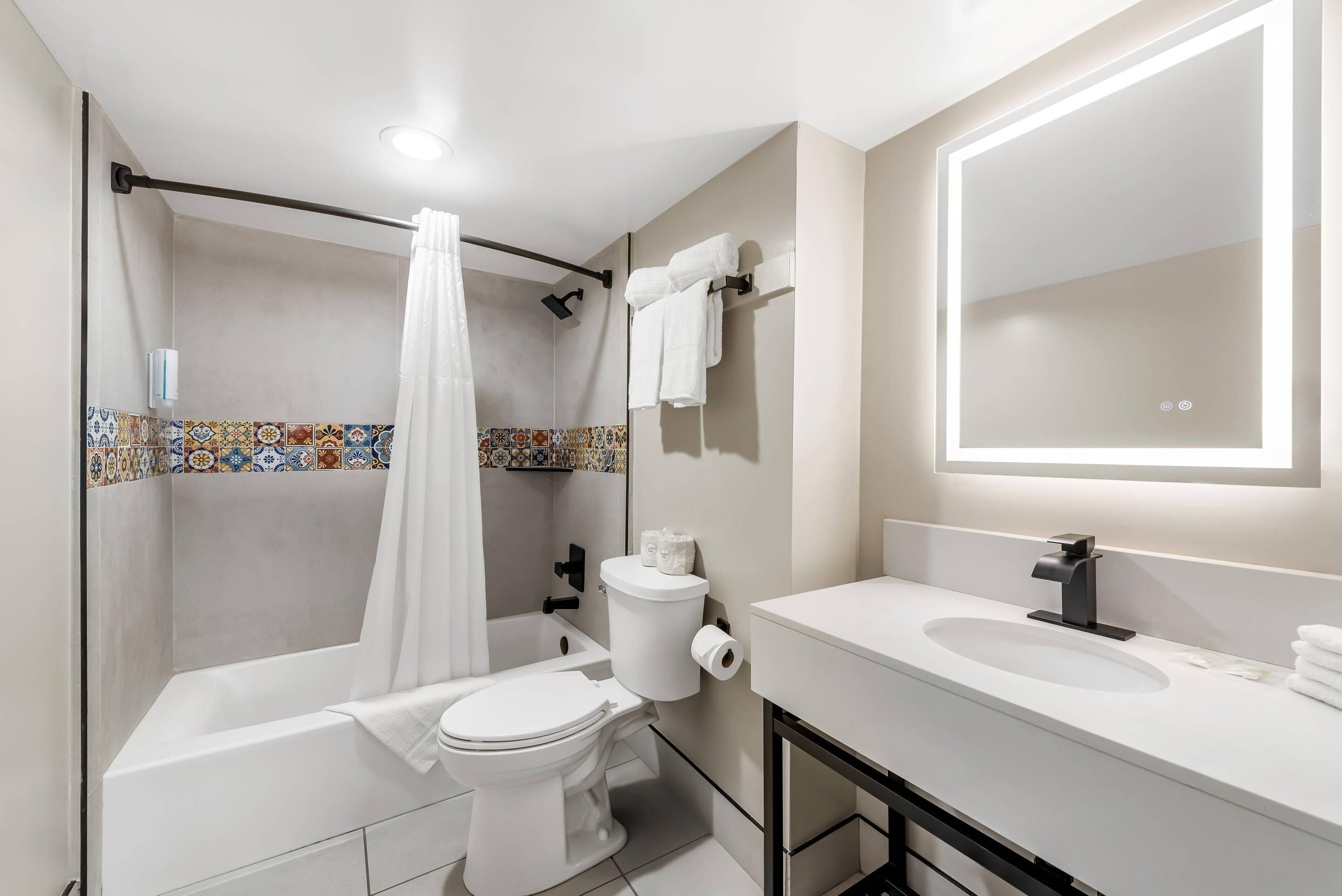A bathroom with a shower, toilet, sink, and a mirror.