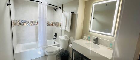 A bathroom with a bathtub, toilet, sink, and a mirror.
