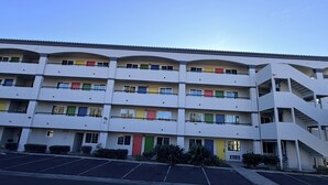 A multi-story building with balconies, a parking lot, and a staircase.