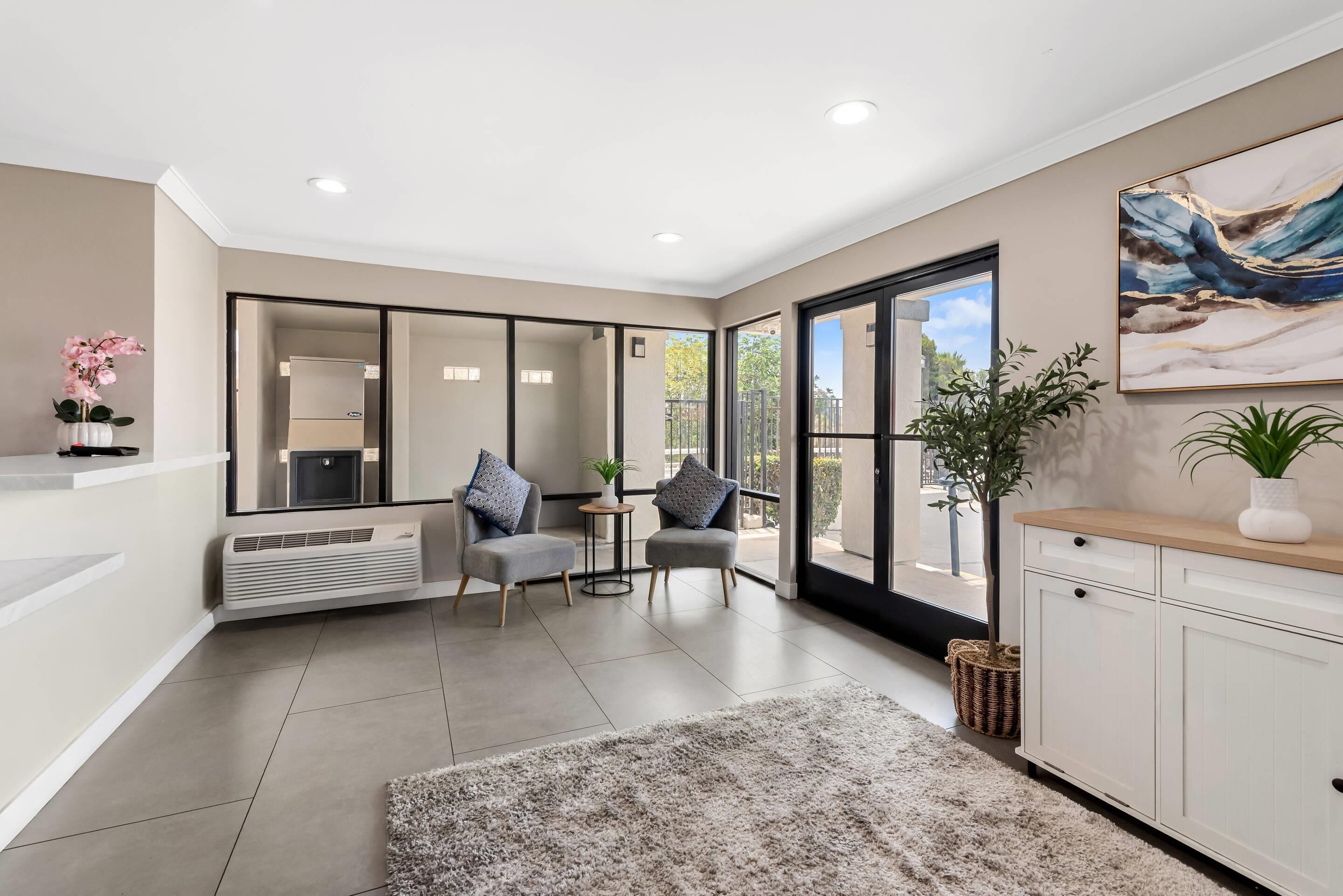 A modern living room with a large window, a fireplace, and a kitchen area.