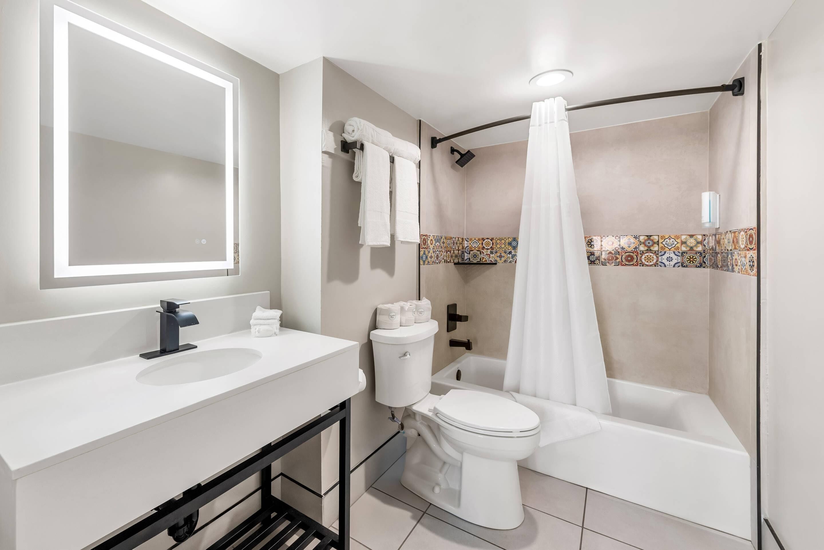 A modern bathroom with a white sink, a toilet, and a shower with a curtain.