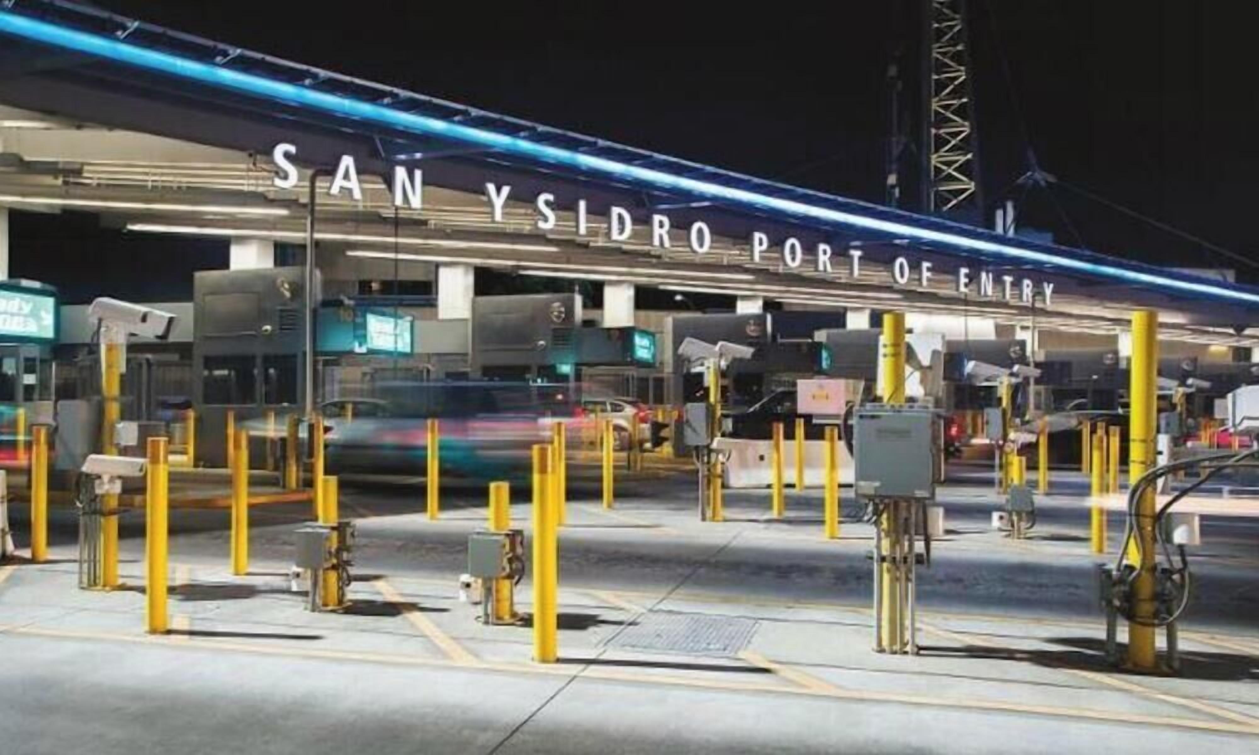 Un point de passage frontalier avec une pancarte indiquant : « POSTE DE PASSE-FRONTIÈRE DE SAN YSIDRO ».