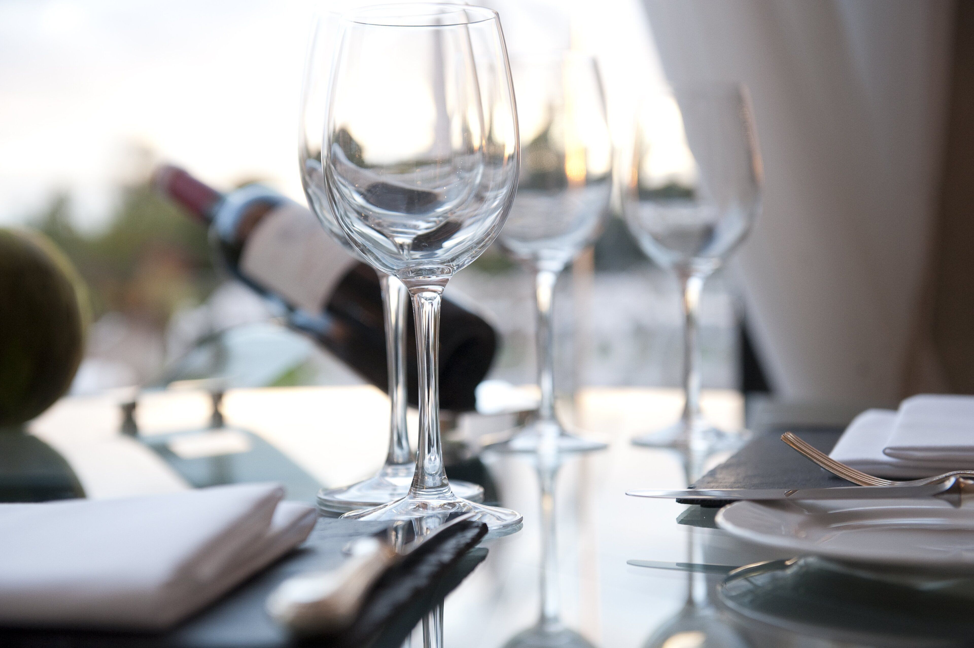 A dining table with empty wine glasses and cutlery, suggesting a formal dining setting.