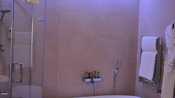A modern bathroom with a freestanding bathtub, a glass-enclosed shower, and a vanity with a large sink and towel rack.