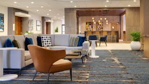 A modern lobby with a sofa, armchairs, a coffee table, and a reception desk. - Holiday Inn San Jose - Silicon Valley by IHG (San Jose)