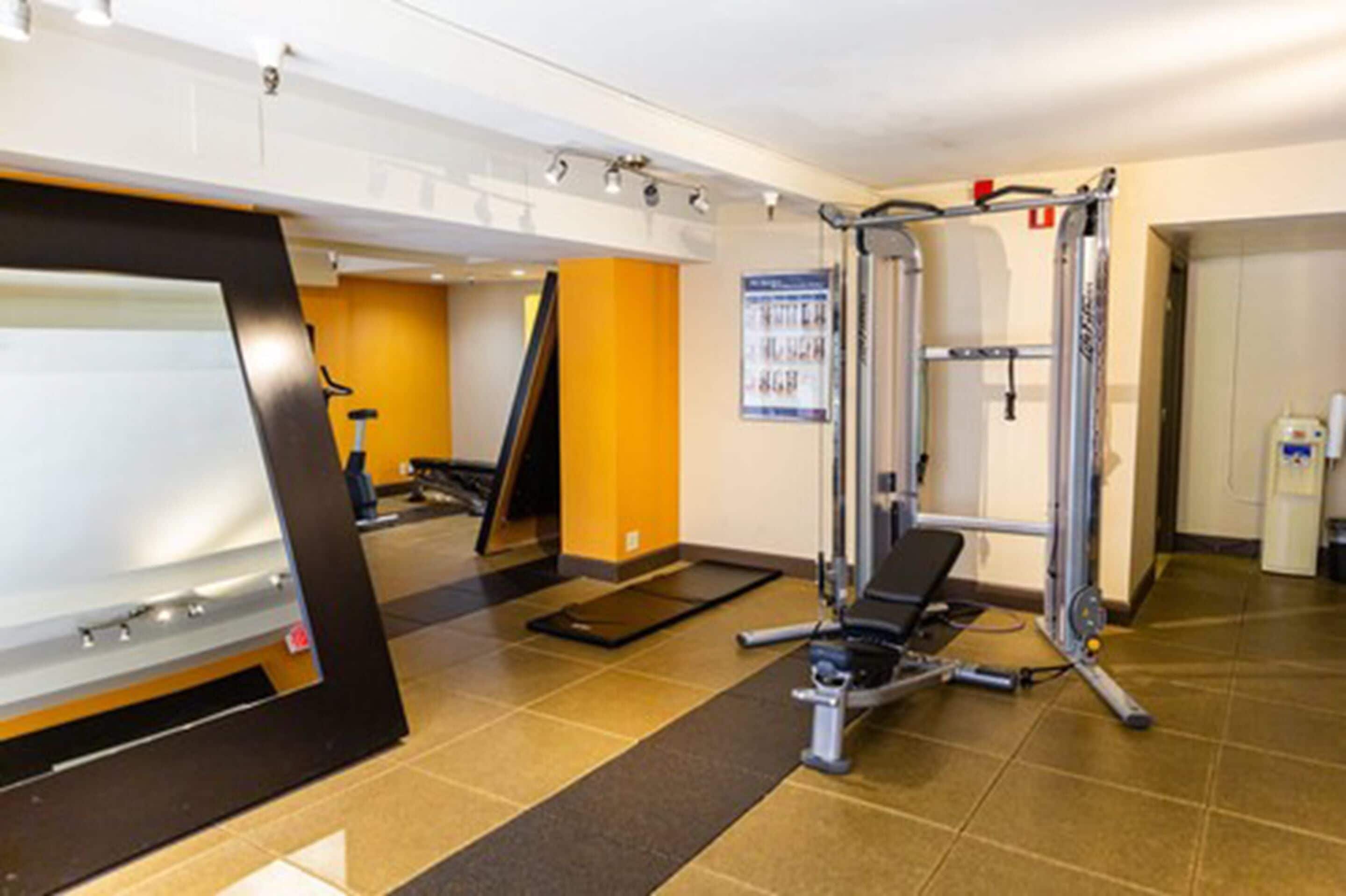 A gym with exercise equipment, a whiteboard, and a poster on the wall.