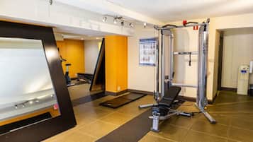 A gym with exercise equipment, a whiteboard, and a poster on the wall.