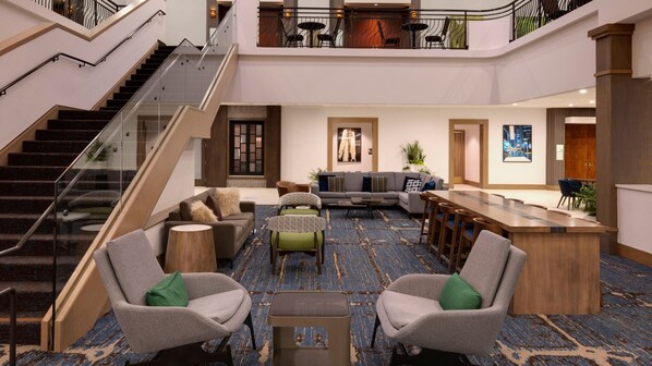 A spacious lobby with a staircase, seating area, and a reception desk. - Holiday Inn San Jose - Silicon Valley by IHG (San Jose)