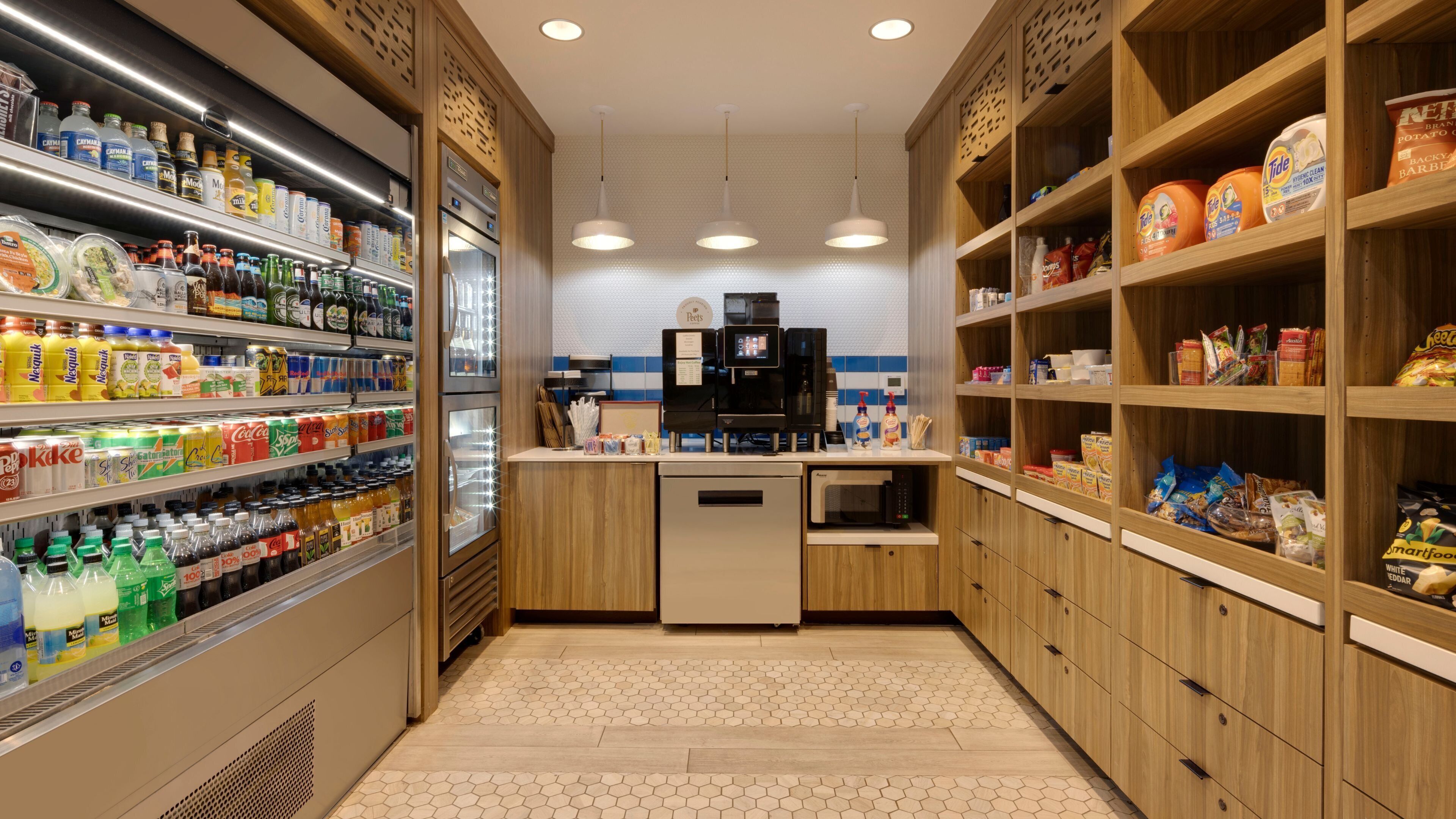 Eine ordentlich eingerichtete Küche mit verschiedenen Lebensmitteln und Getränken auf Regalen, einer Kaffeemaschine und einem Kühlschrank.