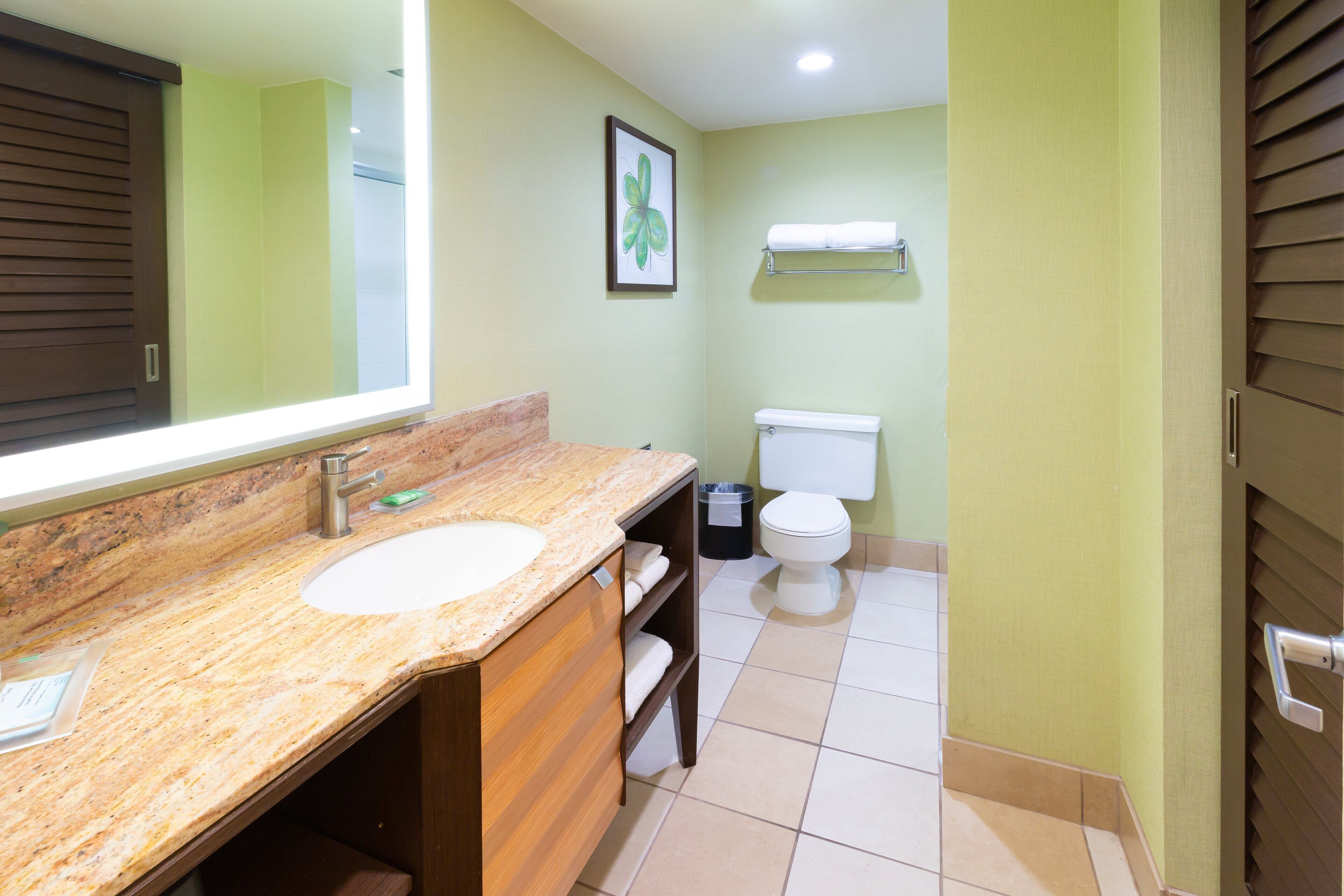 A bathroom with a marble sink, a toilet, and a framed picture on the wall.