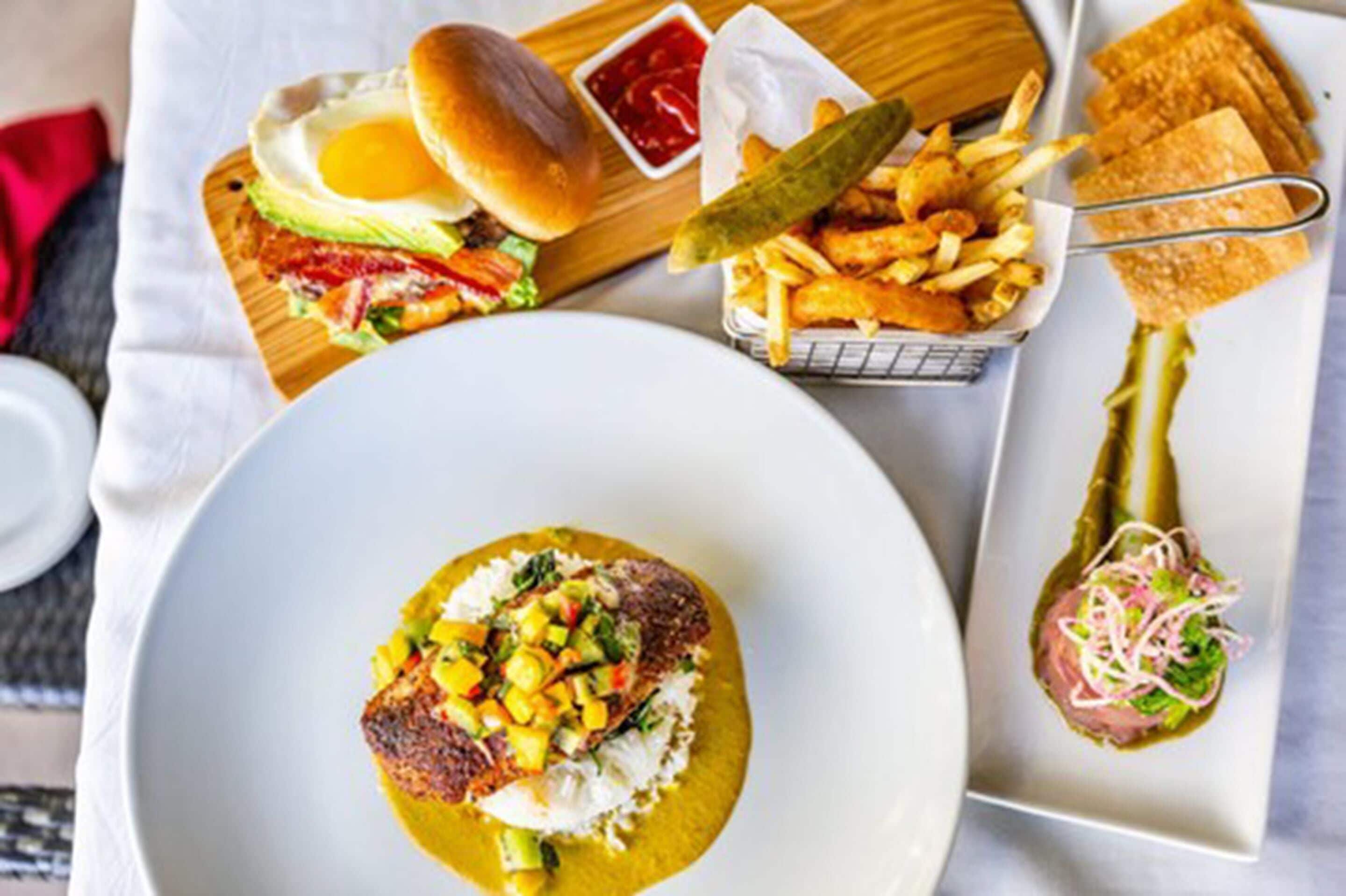 Un choix varié de plats, notamment un hamburger, des frites, un plat de poisson accompagné de riz et une salade.