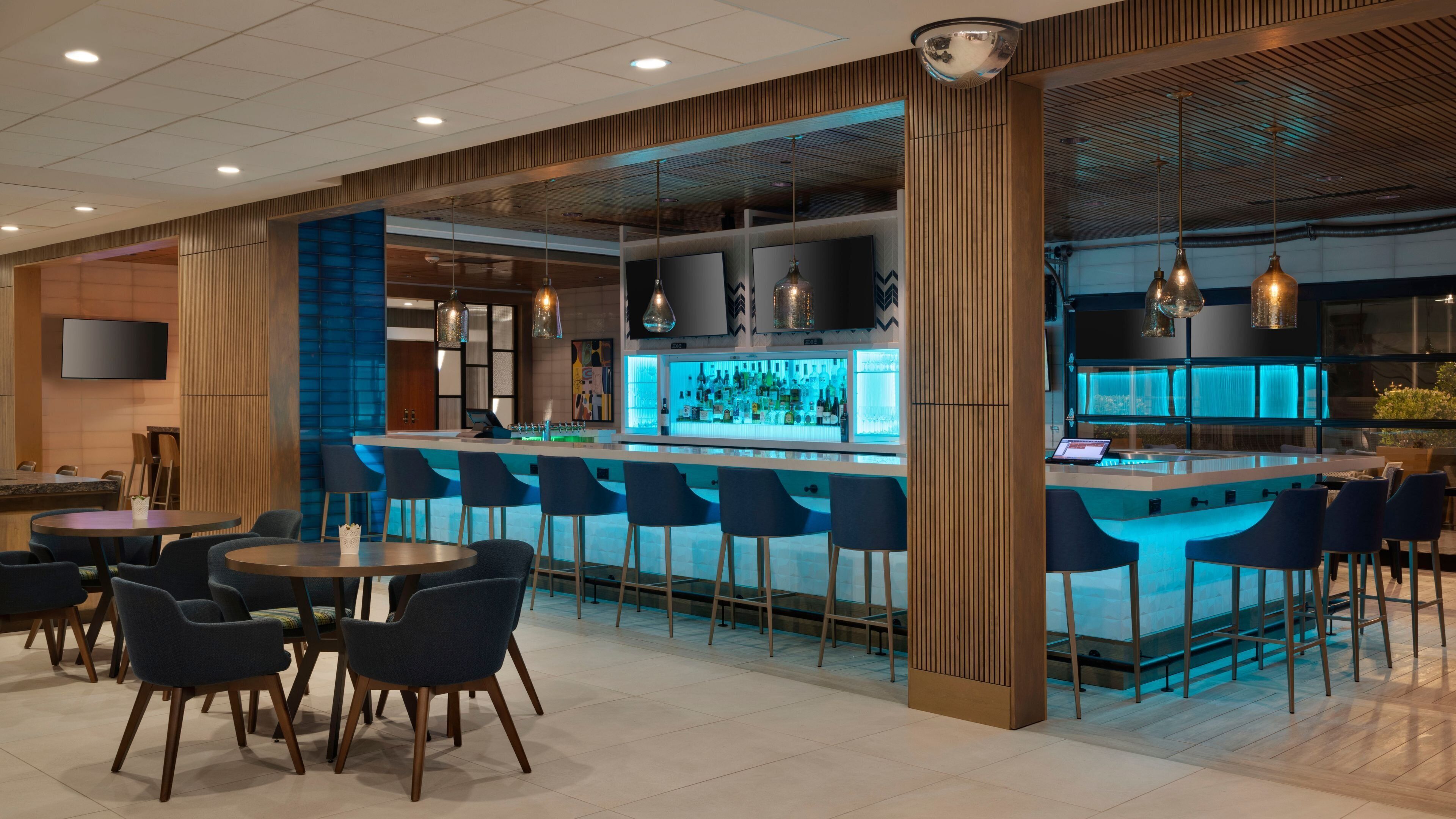 A modern bar area with a bar counter, seating, and a television screen.