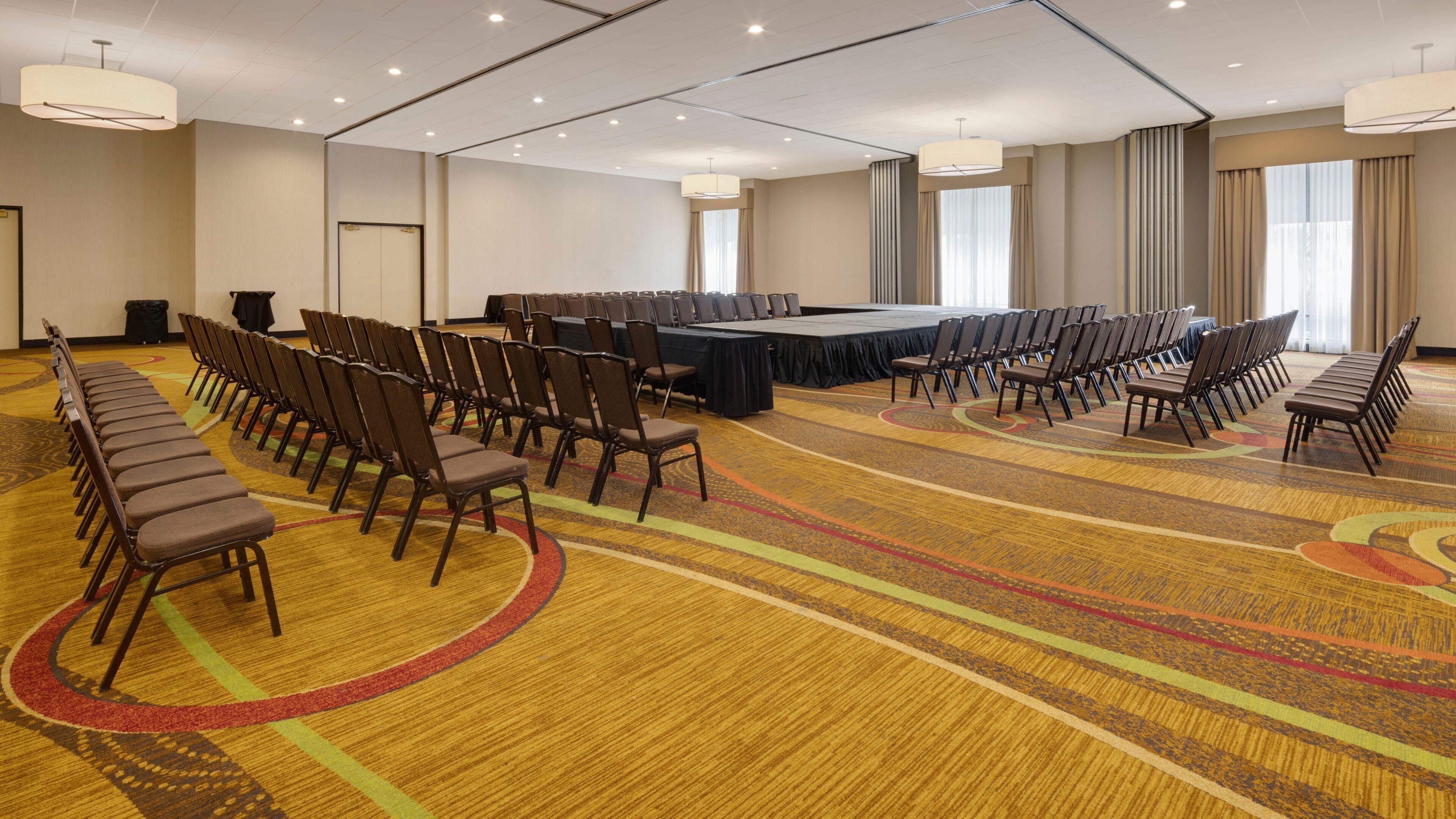 Une salle de conférence avec une longue table, des rangées de chaises et un sol recouvert de moquette.