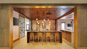 A modern kitchen with a central island, wooden ceiling, and pendant lighting. - Holiday Inn San Jose - Silicon Valley by IHG (San Jose)