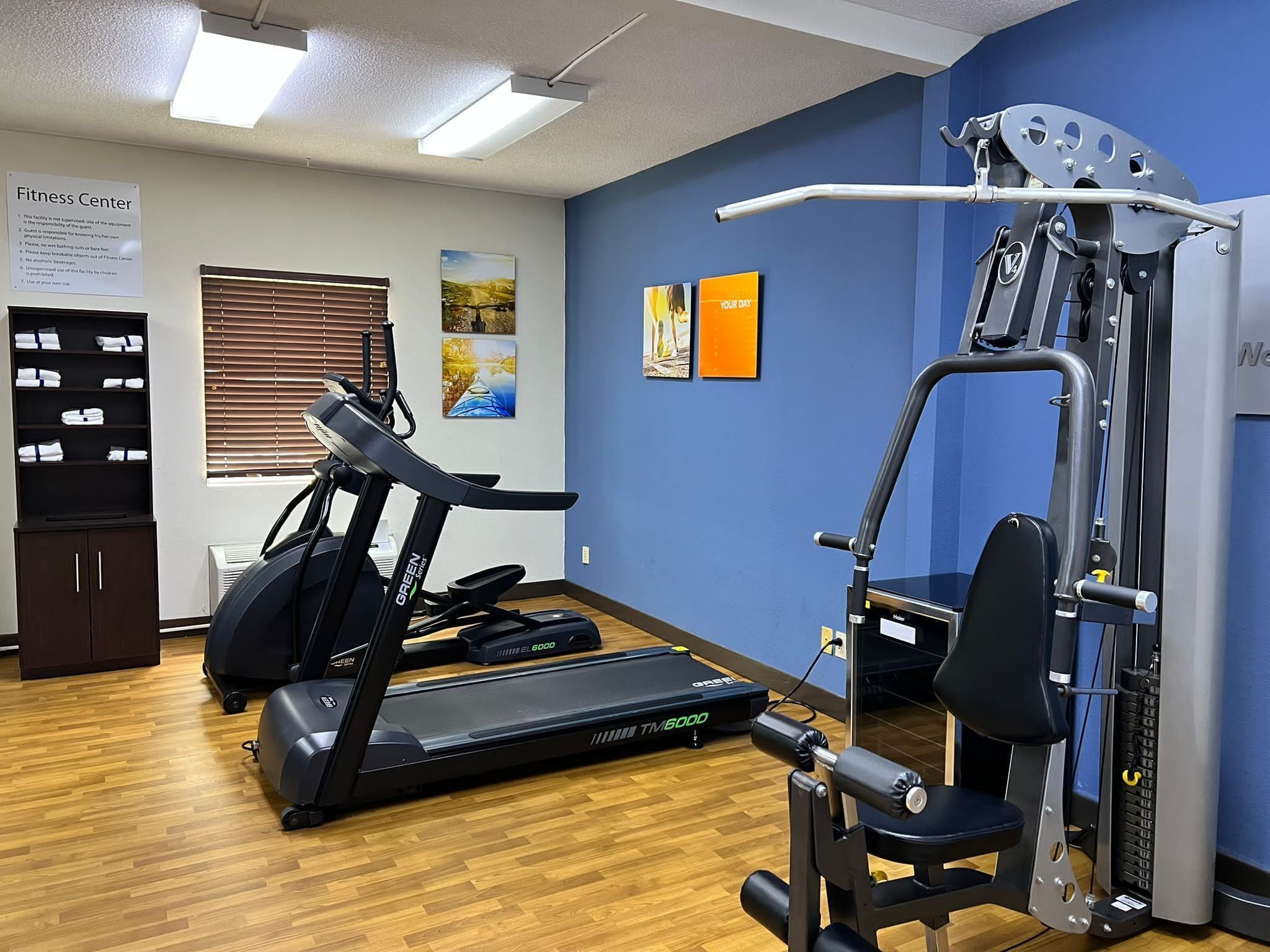 A fitness center with treadmills, a weight machine, and a wall with motivational posters.