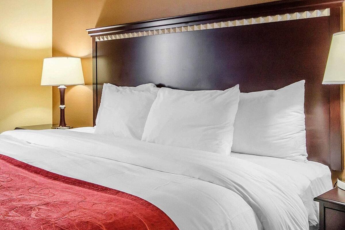 Ett hotellrum med en stor säng, två sänglampor och en sänggavel i trä.