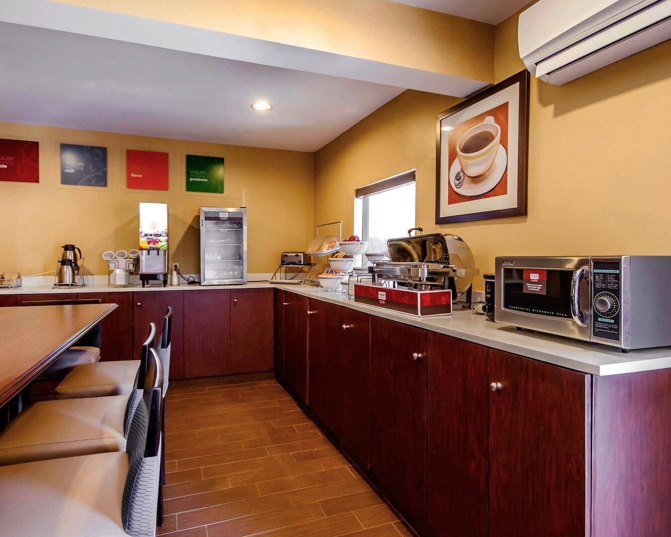 A hotel kitchen with a microwave, coffee machine, and a refrigerator.