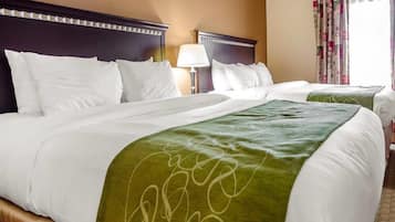 Habitación de hotel con dos camas, cabecero con diseño decorativo, lámpara y ventana con cortinas.