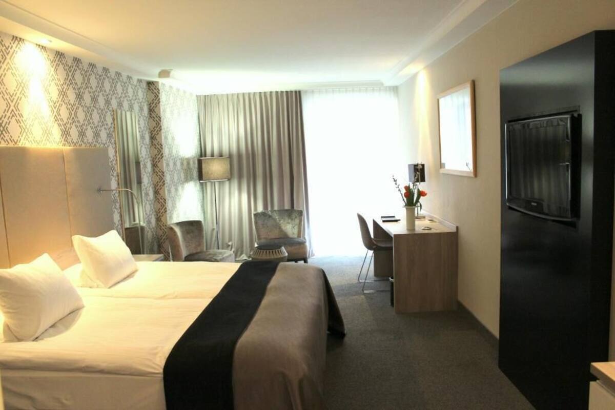 Une chambre d’hôtel avec un grand lit, un bureau, une chaise, une télévision et une porte.