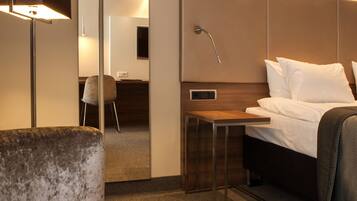 Una habitación de hotel con cama, escritorio, silla y un espejo grande.