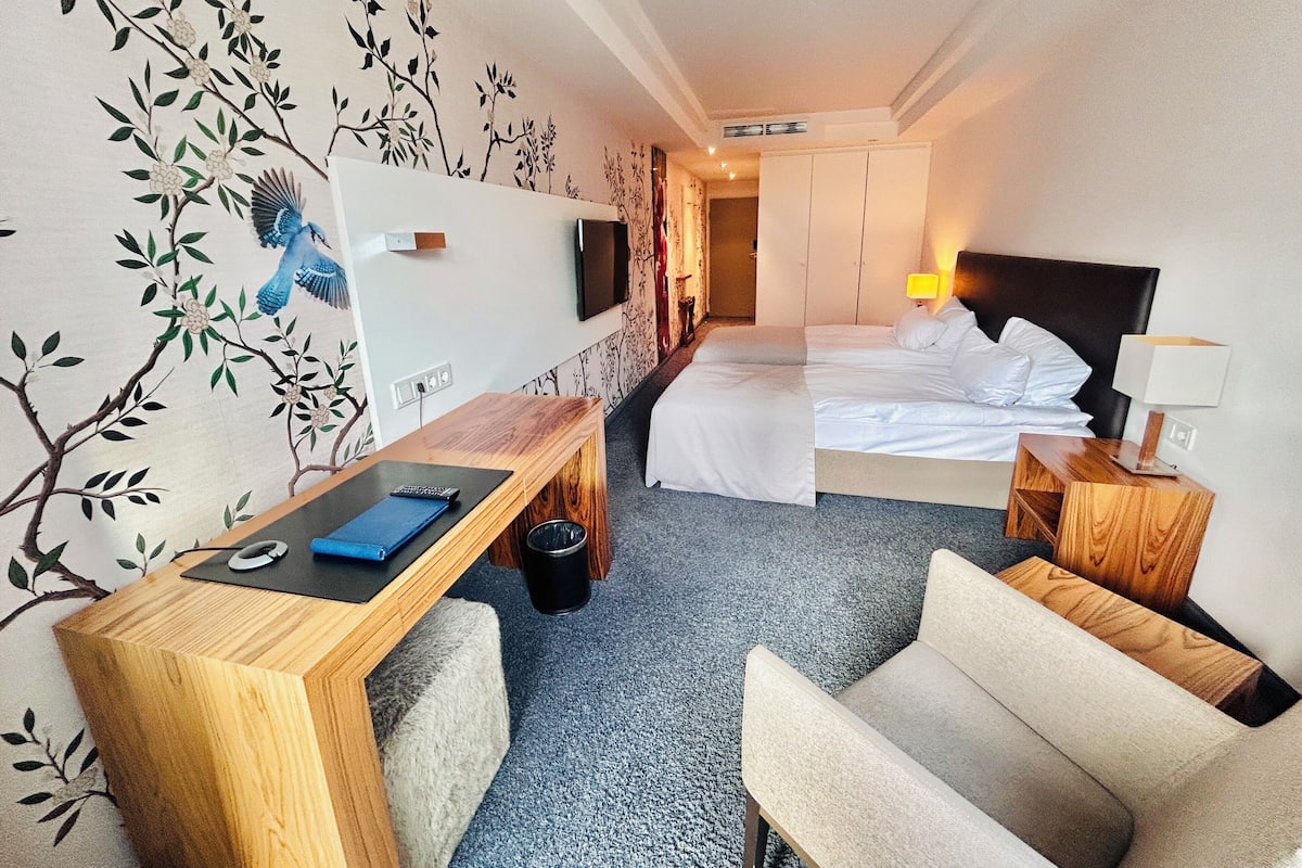 Une chambre d’hôtel avec un lit, un bureau, une chaise, une télévision et une lampe.