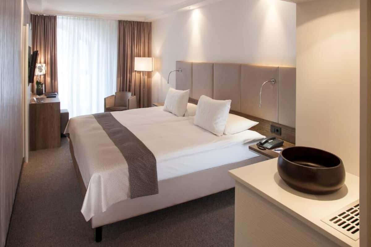 Une chambre d’hôtel dotée d’un grand lit, de tables de chevet, d’un bureau et d’une salle de bain moderne.