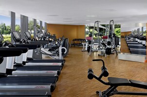 Un gimnasio con cintas de correr, máquinas de pesas y mancuernas.
