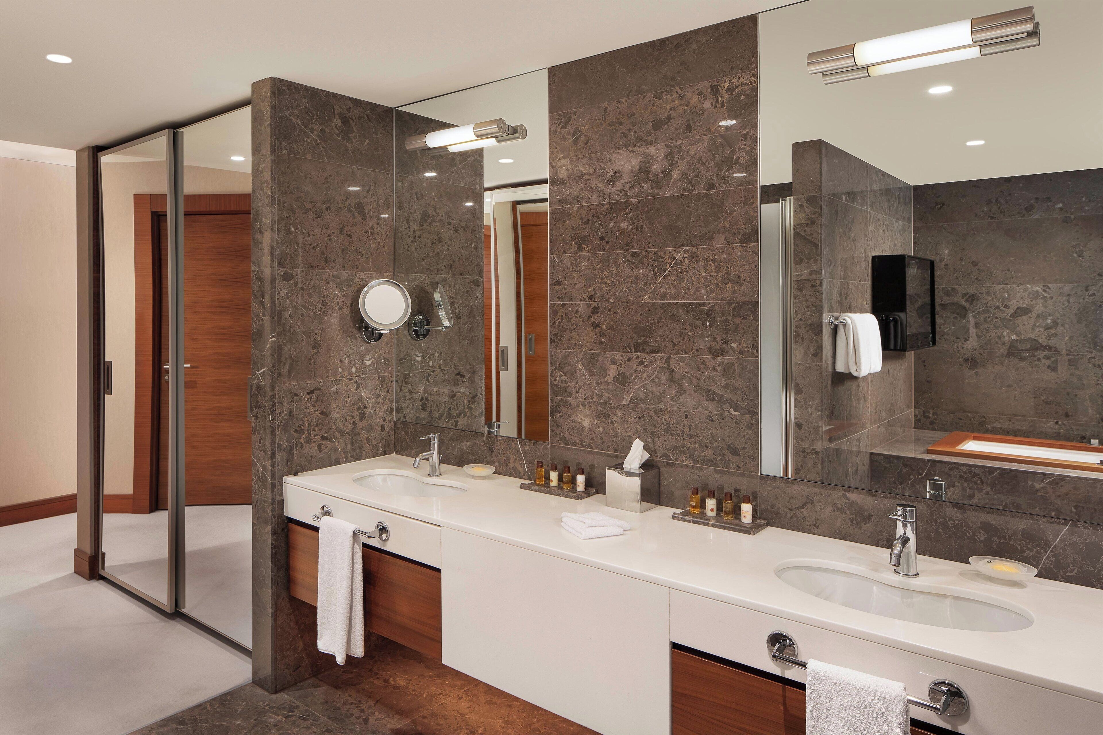 A modern bathroom with two sinks, a glass shower enclosure, and a large mirror.