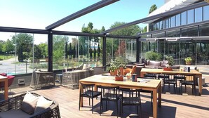 A spacious outdoor area with a wooden table and chairs, wicker furniture, and potted plants. - Sheraton Istanbul Atakoy Hotel (Istanbul)