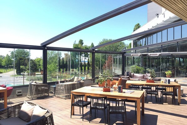 A spacious outdoor area with a wooden table and chairs, wicker furniture, and potted plants. - Sheraton Istanbul Atakoy Hotel (Istanbul)
