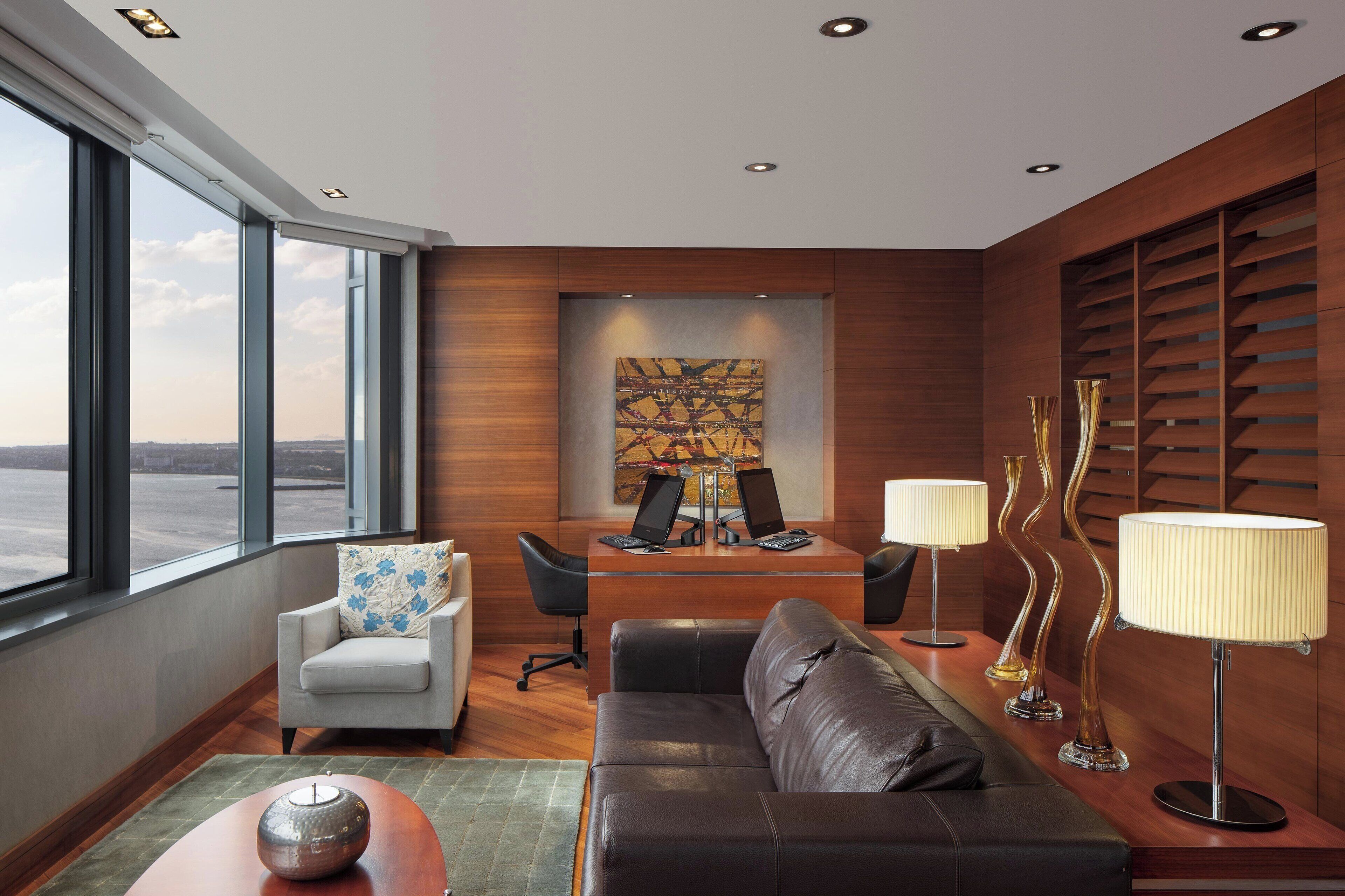A modern office space with a desk, two chairs, a sofa, and a lamp.