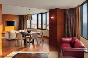 A modern living room with a dining area, a leather sofa, and a large window offering a city view.