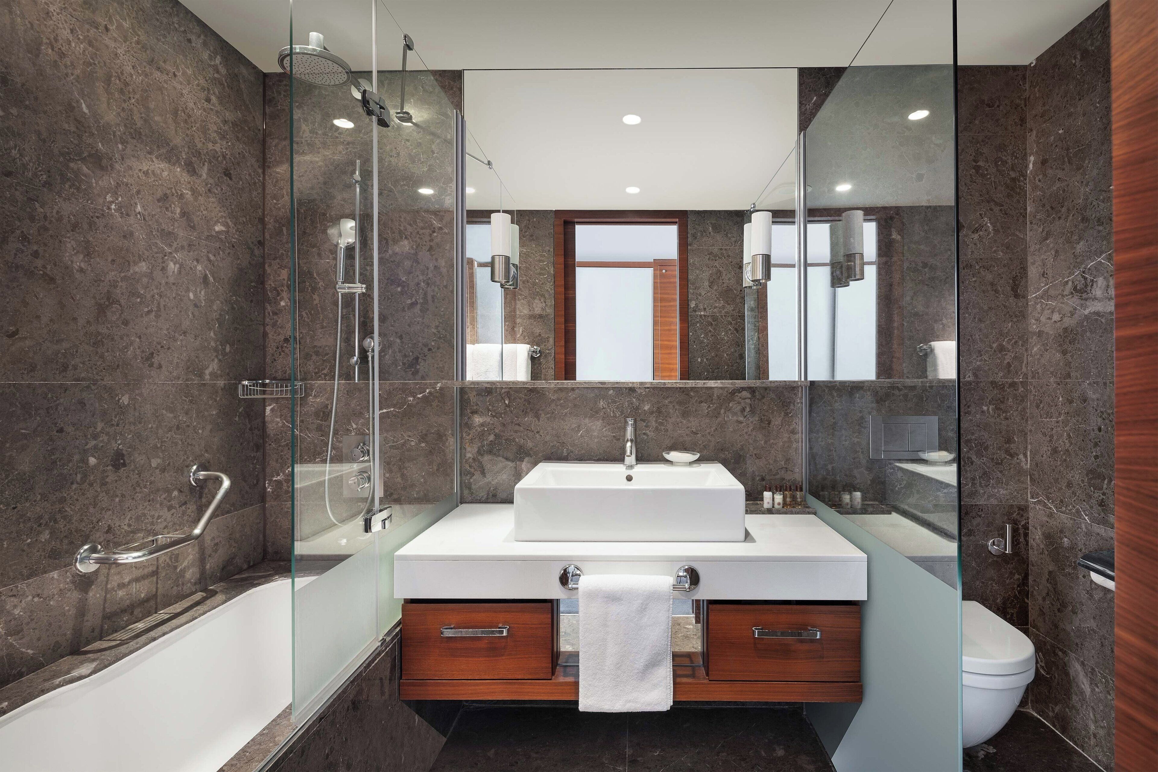 A modern bathroom with a glass-enclosed shower, a white sink, and a wooden vanity.