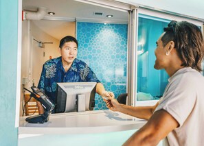 A reception area with a counter, a computer, and a blue patterned wall. - Waikiki Circle Hotel By Castle (Honolulu)
