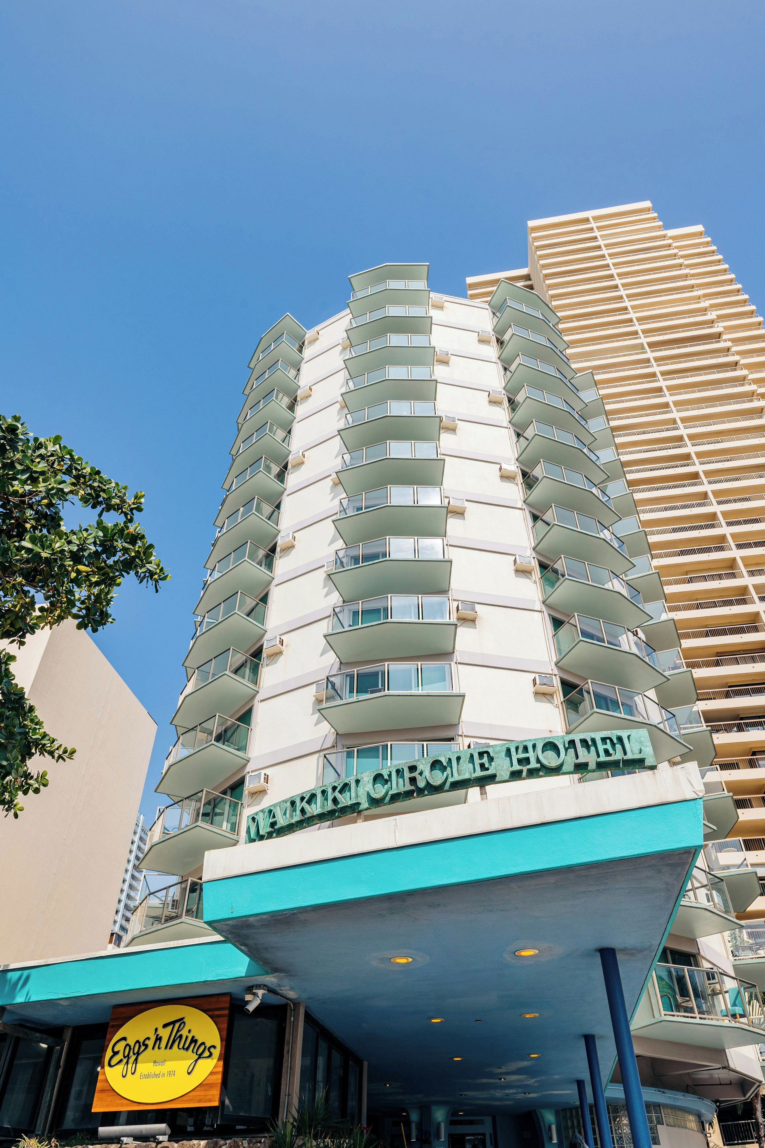 A hotel with a modern design, featuring multiple balconies and a prominent sign.