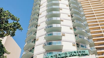 A hotel with a modern design, featuring multiple balconies and a prominent sign.