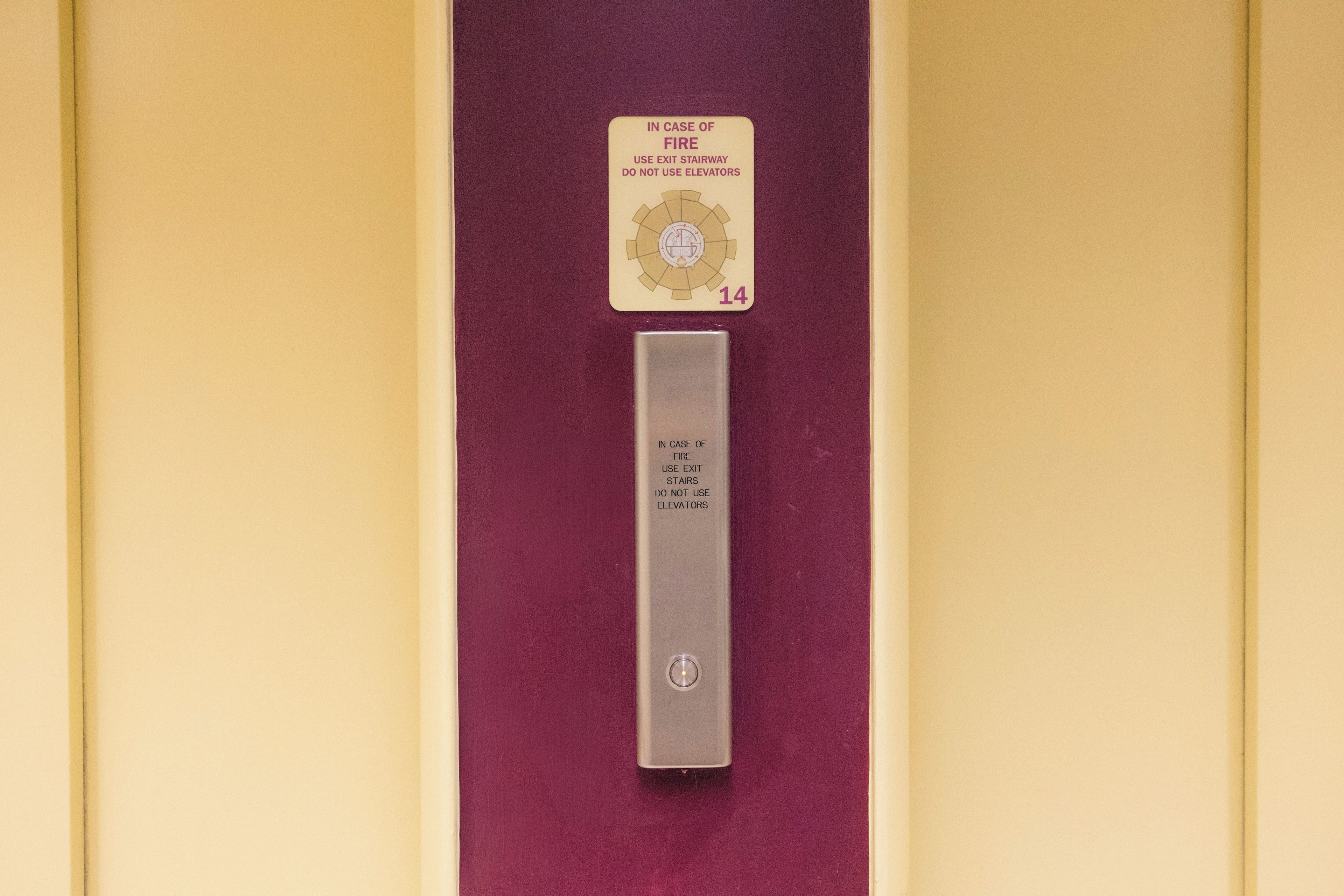 A fire safety card and a metal plate with instructions for use of exit stairs and avoidance of elevators in case of fire.