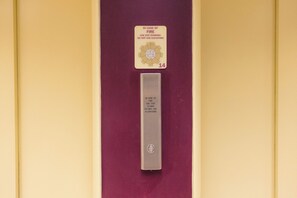 Tarjeta de seguridad contra incendios y una placa metálica con instrucciones para usar las escaleras de emergencia y evitar los ascensores en caso de incendio.